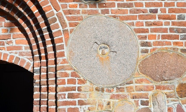 Kamień młyński wmurowany w fasadę kościoła