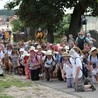 Pielgrzymi piesi z Płocka na Jasną Górę: jedna grupa przyklęka przed kościołem, kolejna zbliża się do miejscowości w parafii św. Benedykta w Płocku Radziwiu