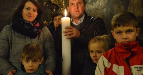 Rodzina ze świecą jubileuszową 1050. rocznicy chrztu Polski